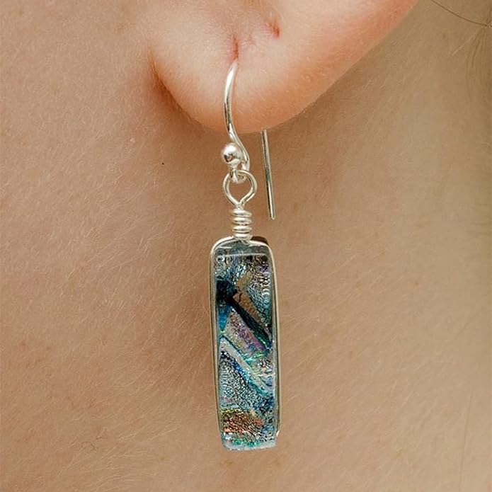Multicolored silver earring in a rectangular shapee worn on an ear.