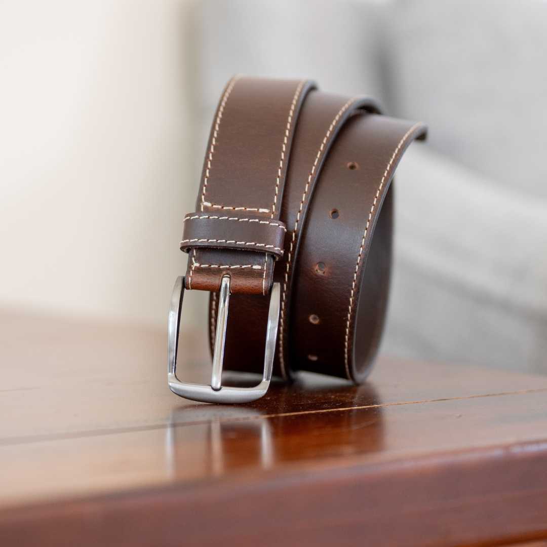 nickel free silver belt buckle with brown leather strap 1.5 inch wide with cream stitching.