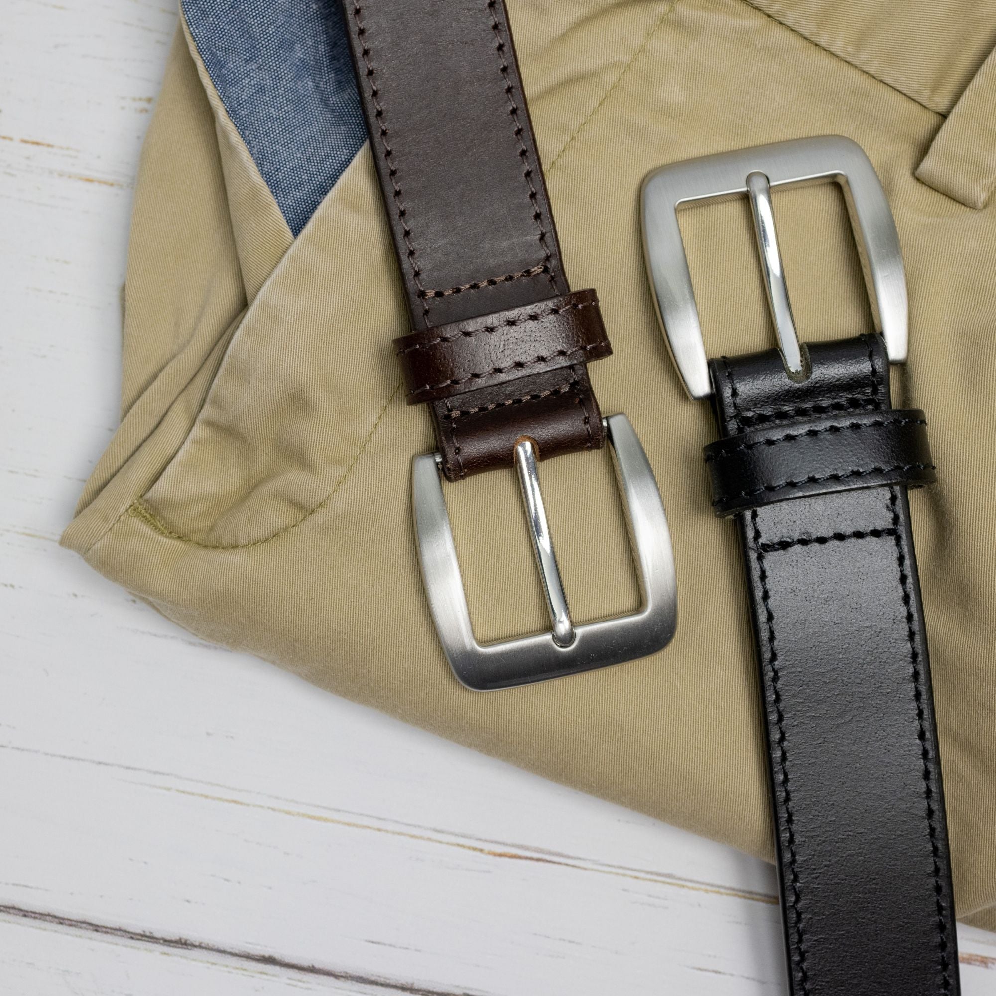One brown strap, one black. Single-stitched edges. Rounded buckles.
