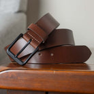 Black matte buckle with brown leather strap sitting on table. 1.5 inches