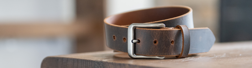 Roan Mountain Distressed Leather Belt sitting on wood table