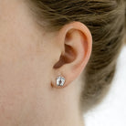 A tiny pair of footprint earrings on a model. Stud earrings.