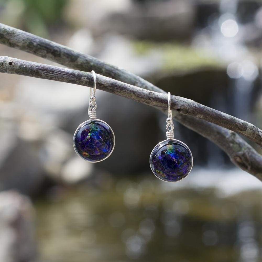 Jupiter Earrings. Outdoor setting. Circular dangles made from dark purple dichroic glass.