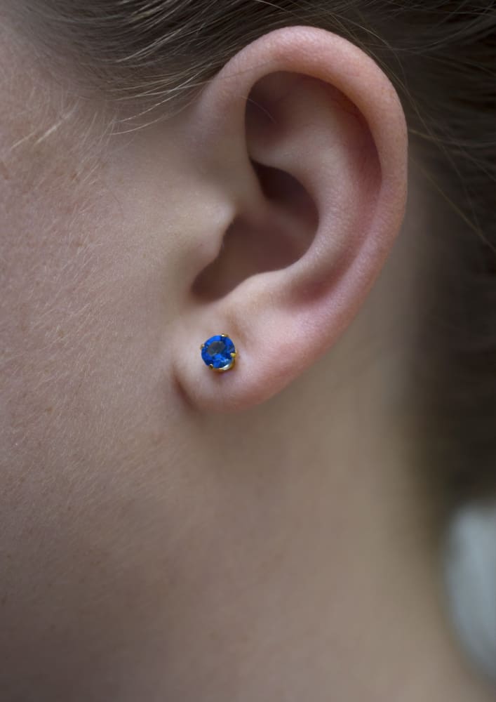 Sapphire Sparkle Posts on model. No rash! Bright blue earrings with golden hypoallergenic materials.